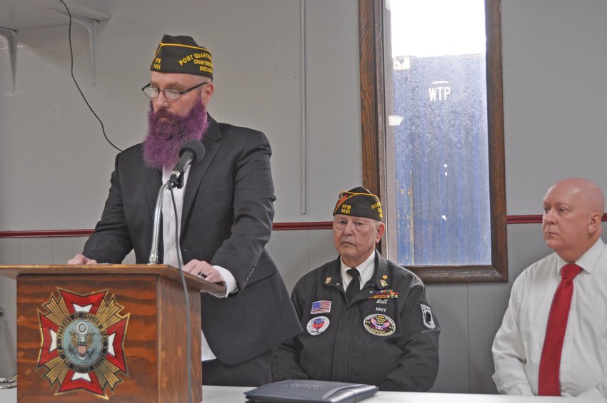 Jason Black, quartermaster of Brian Bowman VFW Post 1431, delivers remarks at a Veterans Day ceremony as post commander Gary Bell and Crawfordsville Mayor Todd Barton listen at the post on Thursday.
