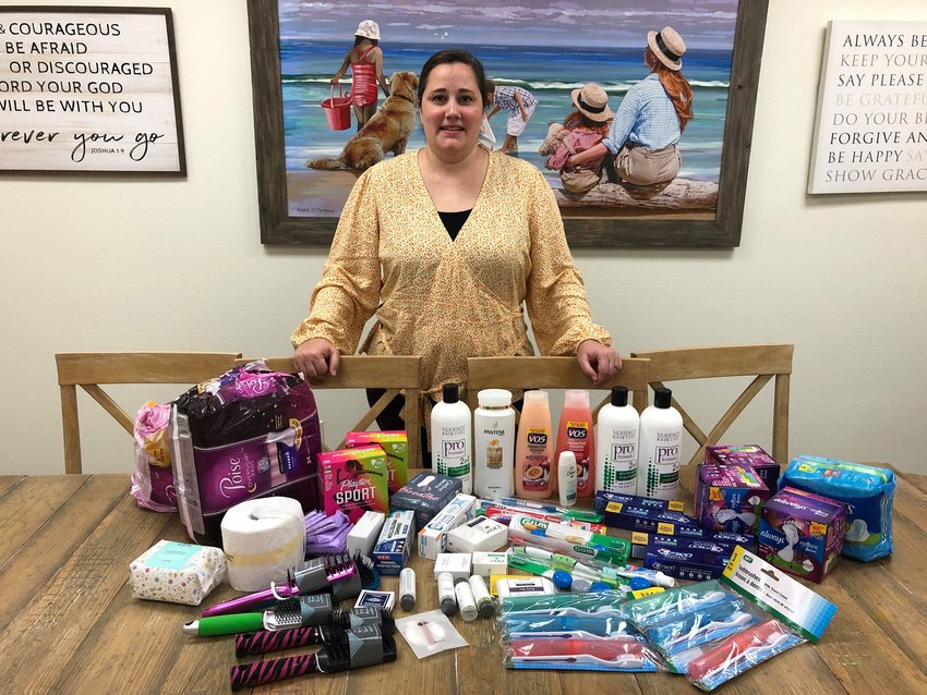 Katy Cares Social Services Director Kristin Dean poses with donations to Katy Cares that were gathered via a supply drive at the YMCA. Katy Cares depends on donations to help them support single-parent families with essential needs such as toiletries and food as well as to fund its counseling and education services.