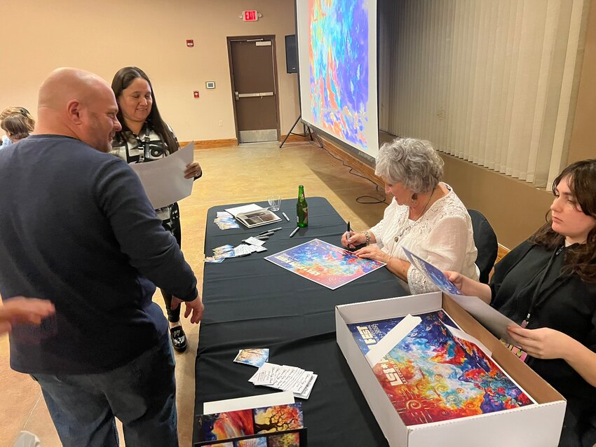 Poster artist Vicki Henley signs copies of the poster for everyone who attended the 2024 LCCIFF poster reveal party.