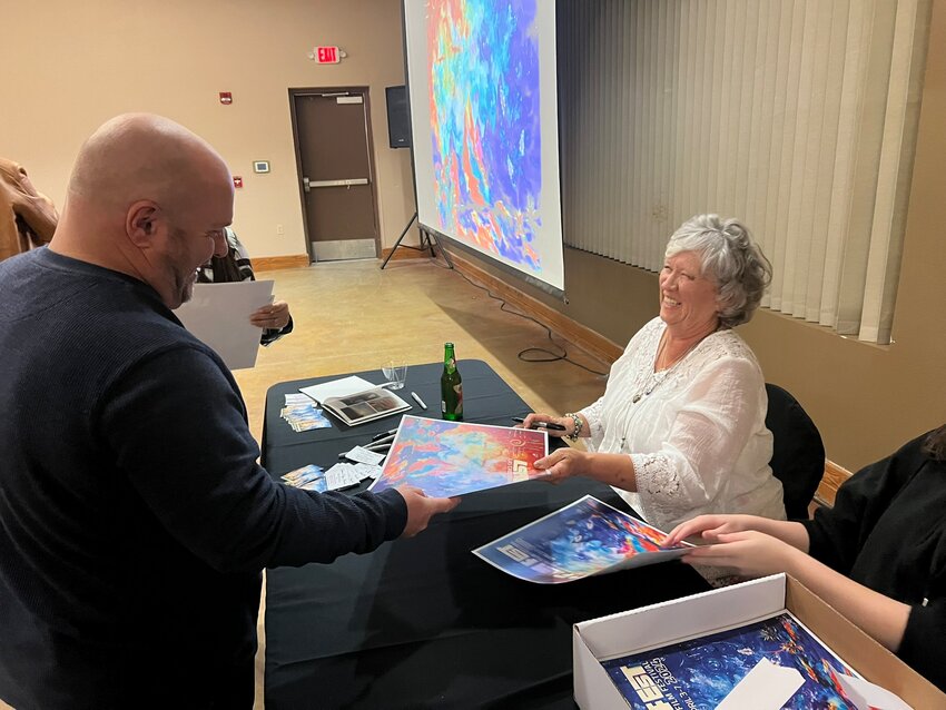 Poster artist Vicki Henley signs copies of the poster for everyone who attended the 2024 LCCIFF poster reveal party.