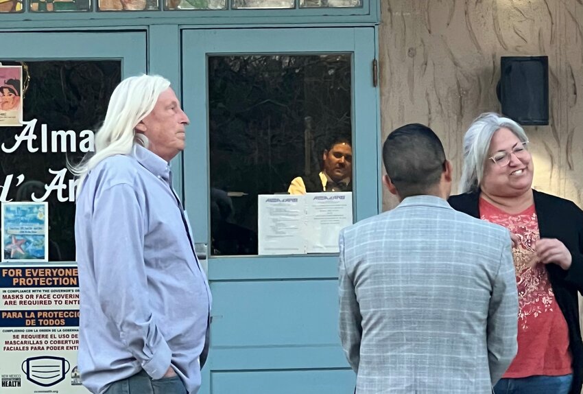 After a governing board meeting on April 15, Alma d’Arte principal Adam Amador looks through the front entrance window as members of the public congregate outside.