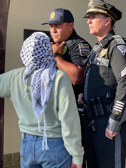 A protester confronts police officers barring entry to the Hadley administration building at New Mexico State University in Las Cruces on May 9, 2024.