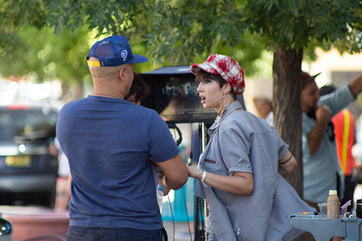 Co-star Jackie Cruz discusses a scene with a crewman.