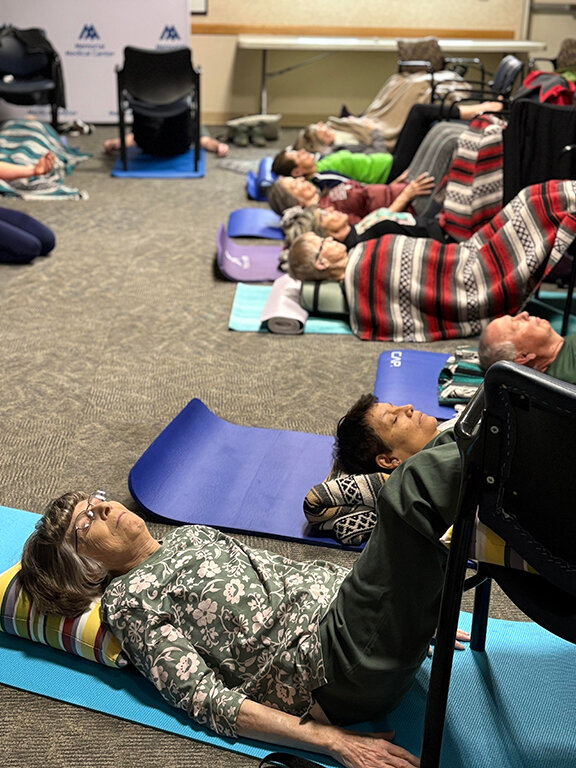 Several attendees relax in a yoga position to elevate their legs and help with posture. Classes are held every Monday at noon and Friday at 5:30 p.m.