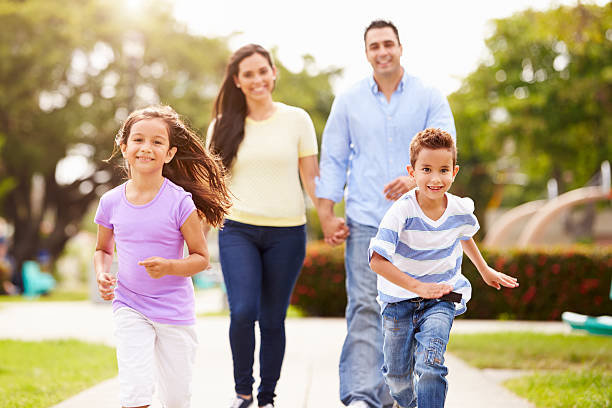 Hispanic Family Walking In Park Together Children Running Ahead Smiling
