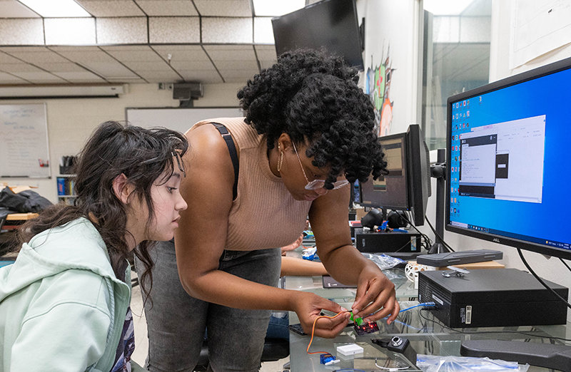 Chioma Abed-Amazu an NMSU graduate student  works with Kaylee Zeledon during the NM Prep students summer camp working on machine learning in the Aggie Innovation Space, Friday June 10, 2022. (NMSU photo by Josh Bachman)