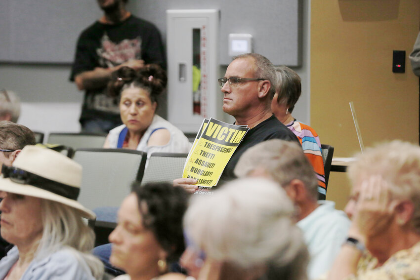 Tim Jenkins, a member of the group Businesses for a Safer Las Cruces, holds a sign reading &quot;Victim&quot; during the city council meeting on April 29.