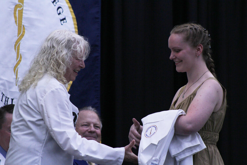 Maggie Gilbert, right, receives her white physicians’ coat during Burrell College of Osteopathic Medicine’s welcoming ceremony in Las Cruces on July 19, 2024.
