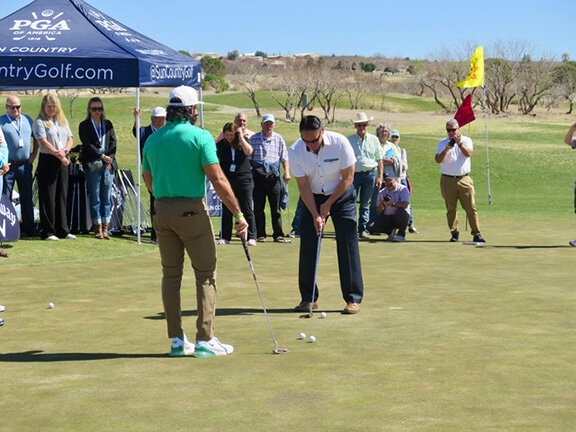 Lt. Gov. Howie Morales gets a putting lesson from celebrity pro Manolo Vega.