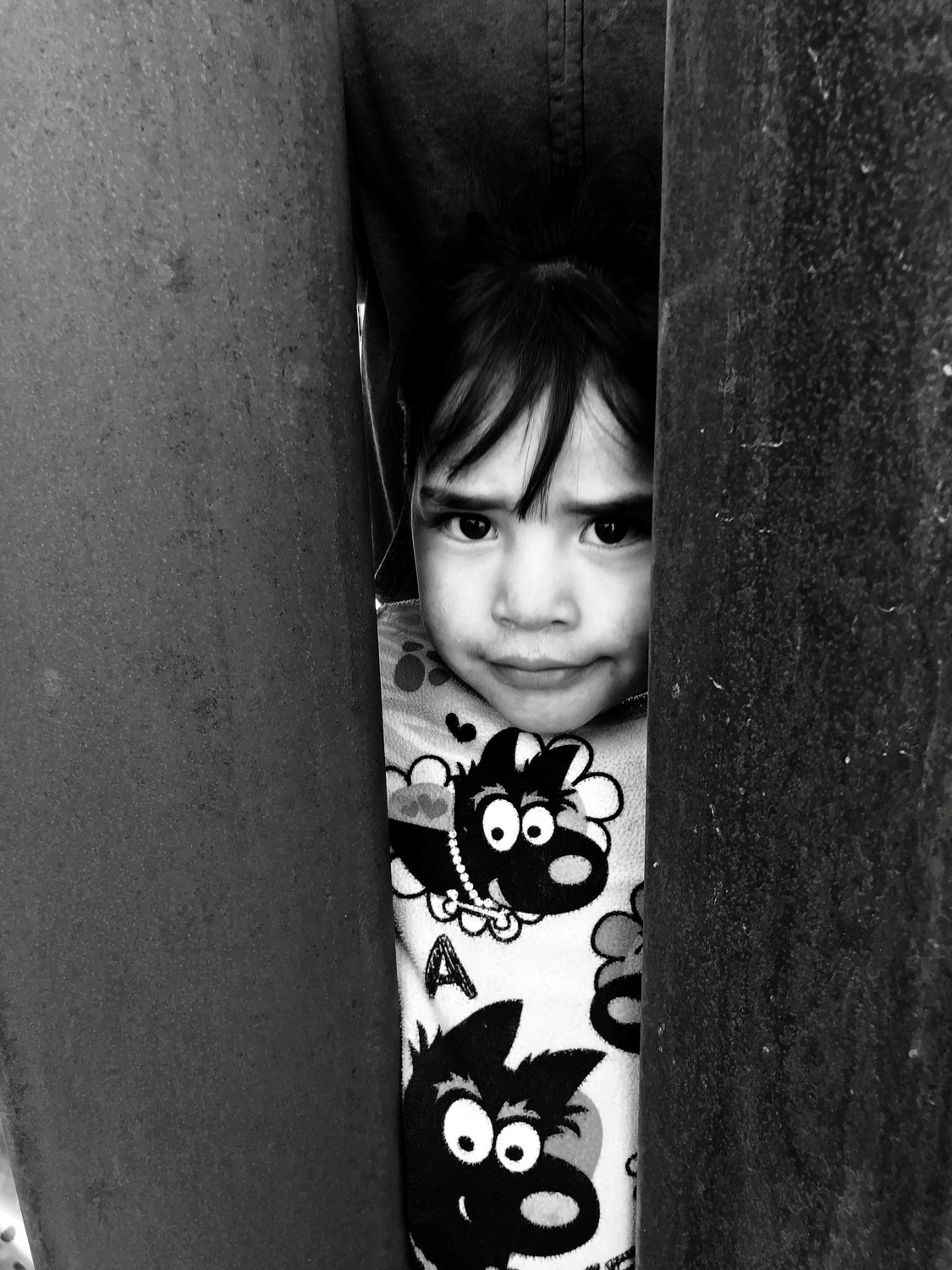 Mexican girl looking through border wall.