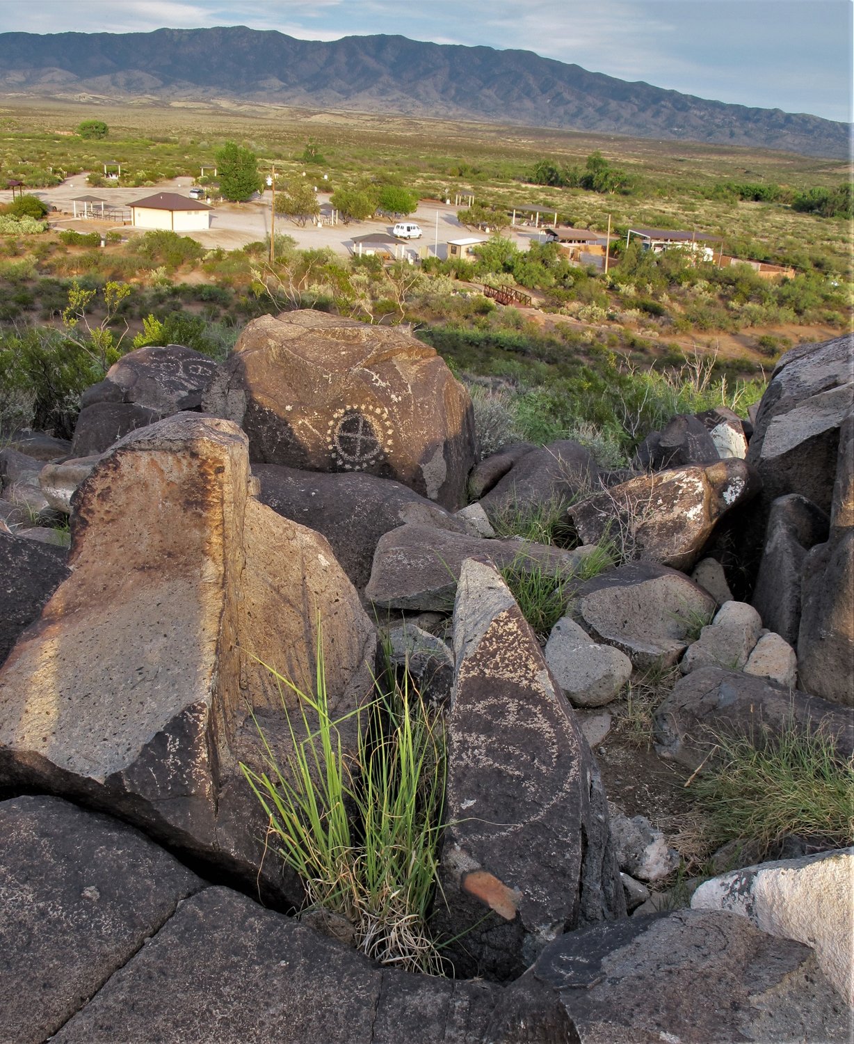 On Summer Solstice sunset, half of a face on a cone shape stone casts a cone shadow into a circle and cross behind it at Three Rivers Petroglyph Site.