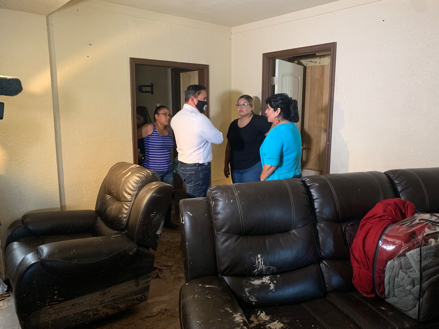 New Mexico Lt. Gov. Howie Morales, front left, and state Rep. Doreen Gallegos chat with Patricia Viramontes and Amber Aguirre in the living room of the mud-filled Aguirre home.