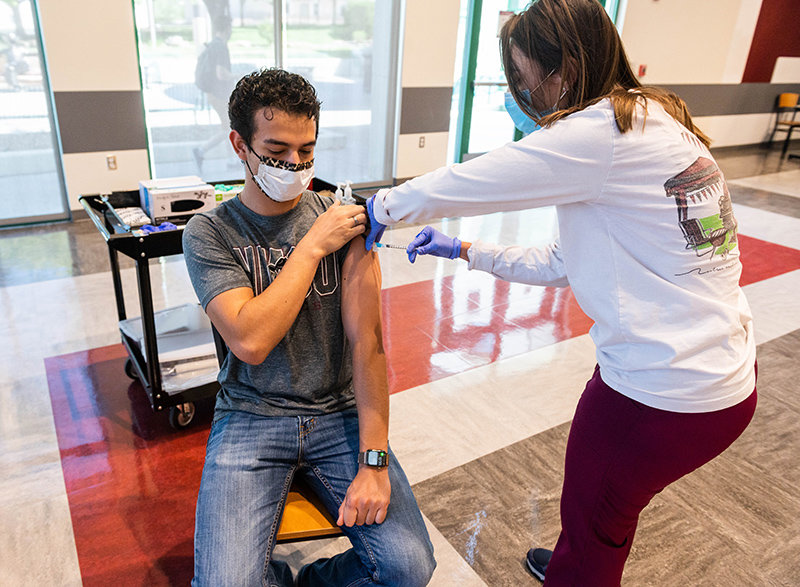 Aggie Health and Wellness Center nurse Marissa Archuleta administers a Johnson and Johnson COVID-19 vaccine to Edward Torres during a walk-in clinic at Corbett Center in May. The New Mexico State University system is requiring all students and employees to become vaccinated or submit weekly proof of a negative COVID-19 test. The university rolled out its online platform for submitting vaccine and testing documentation on Wednesday.