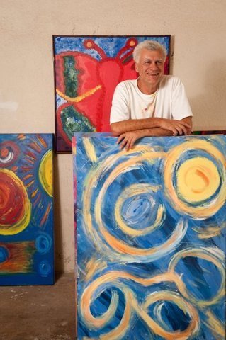 Artist George Mendoza with several of his paintings.