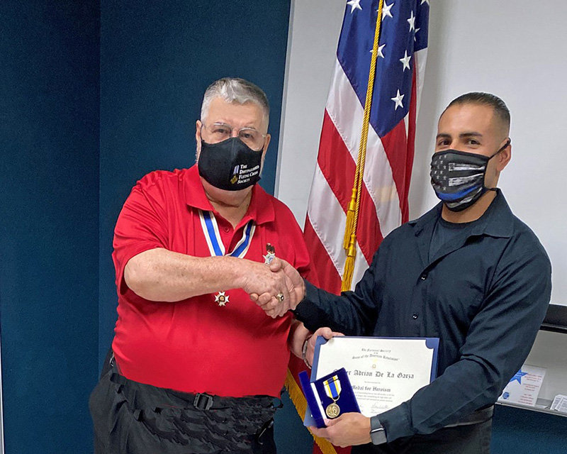 Sons of the American Revolution (SAR) Gadsden Chapter President Don Williams, left, presents an SAR heroism medal to Las Cruces Police Officer Adrian De La Garza.