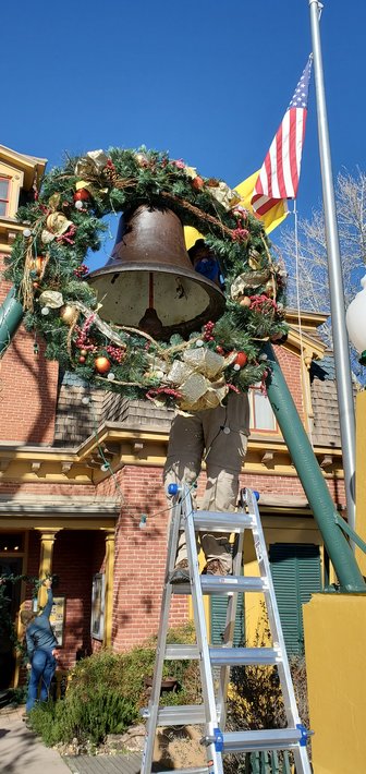 On Saturday, December 11 from 1-5, Victorian Christmas is back! Volunteer Eric Brown hangs a wreath on the bell in front of the museum.