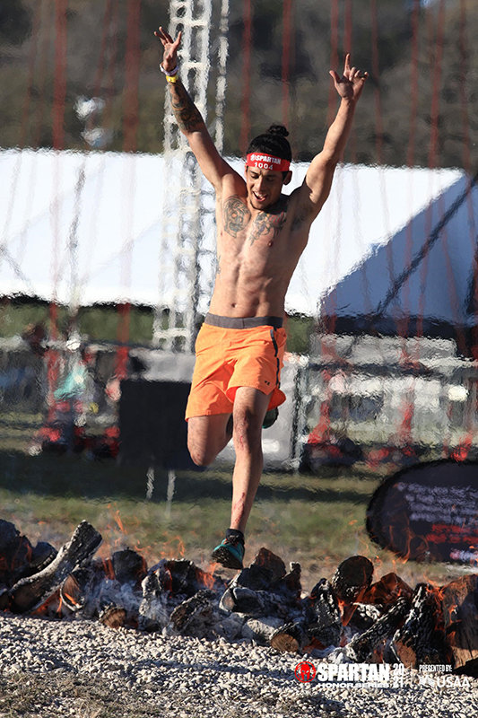Nathan Hidalgo competing in the fire jump obstacle in the Spartan Race event March 21, 2021, in San Antonio, Texas.