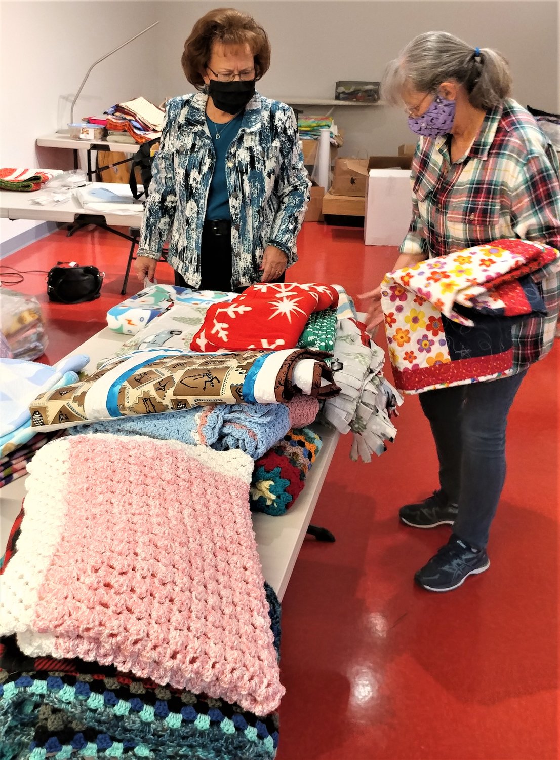 Project Linus Las Cruces chapter members Kathy Mitchell and Debby Schmidt folding, sorting and bagging quilts and blankets for delivery to children in need in Las Cruces and Deming.