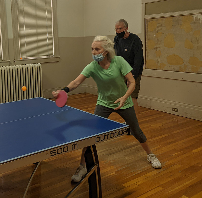 Trudy Buck returns the ball in table tennis at the Frank O’Brien Papen Community Center while doubles partner Dennis Black looks on.