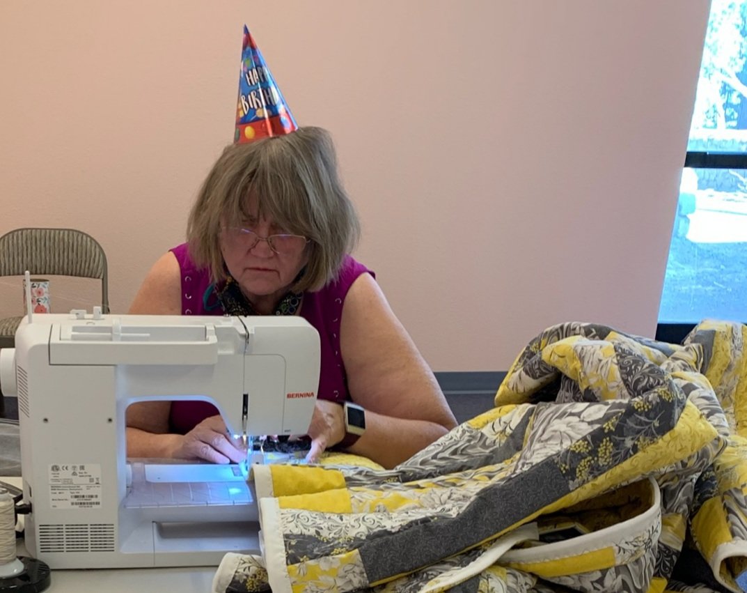 Finishing Michelle's yellow and gray quilt on my birthday while still wearing my party hat.