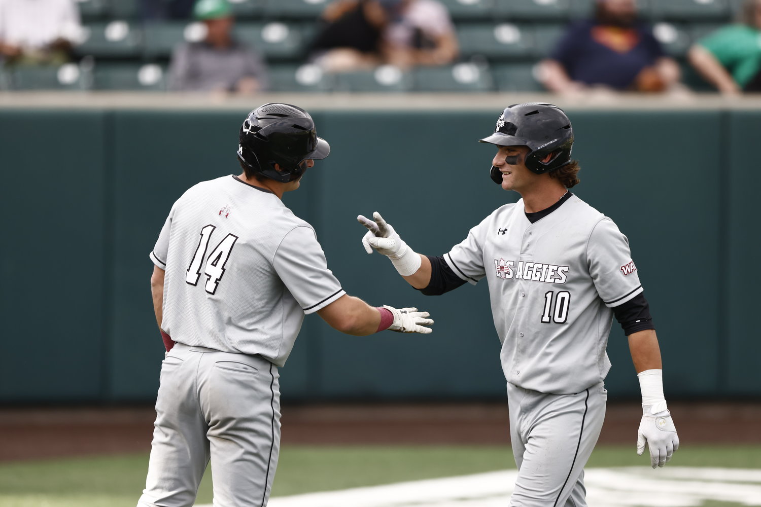 New Mexico State University’s Logan Gallina, 10, and Tommy Tabak, 14, celebrate during the Aggies’ 15-14 win over Utah Valley May 19 in Orem, Utah.