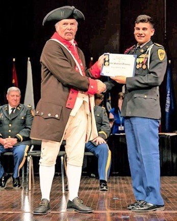 Gadsden Chapter of Sons of the American Revolution compatriot Robert Vance presents the Sons of the American Revolution Junior ROTC bronze medal to Cadet Samuel Ursanic of New Mexico Military Institute in Roswell. Vance was in a Carolina’s period Continental Army uniform.