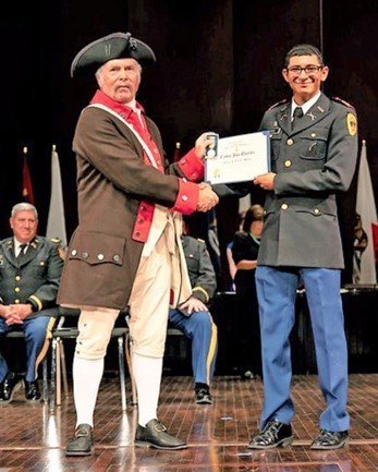 Compatriot Robert Vance presents the Sons of the American Revolution Senior ROTC silver medal to Cadet Joe Quiroz of New Mexico Military Institute in Roswell. Vance was in a Carolina’s period Continental Army uniform.