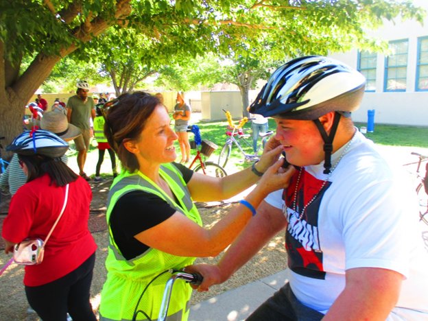 Sevon Negron is fitted for a helmet by Las Cruces Public Schools Safe Routes to Schools Coordinator Ashleigh Curry after receiving his adaptive cycle at the Every Body Rides with Grace Adaptive Cycle Parade.