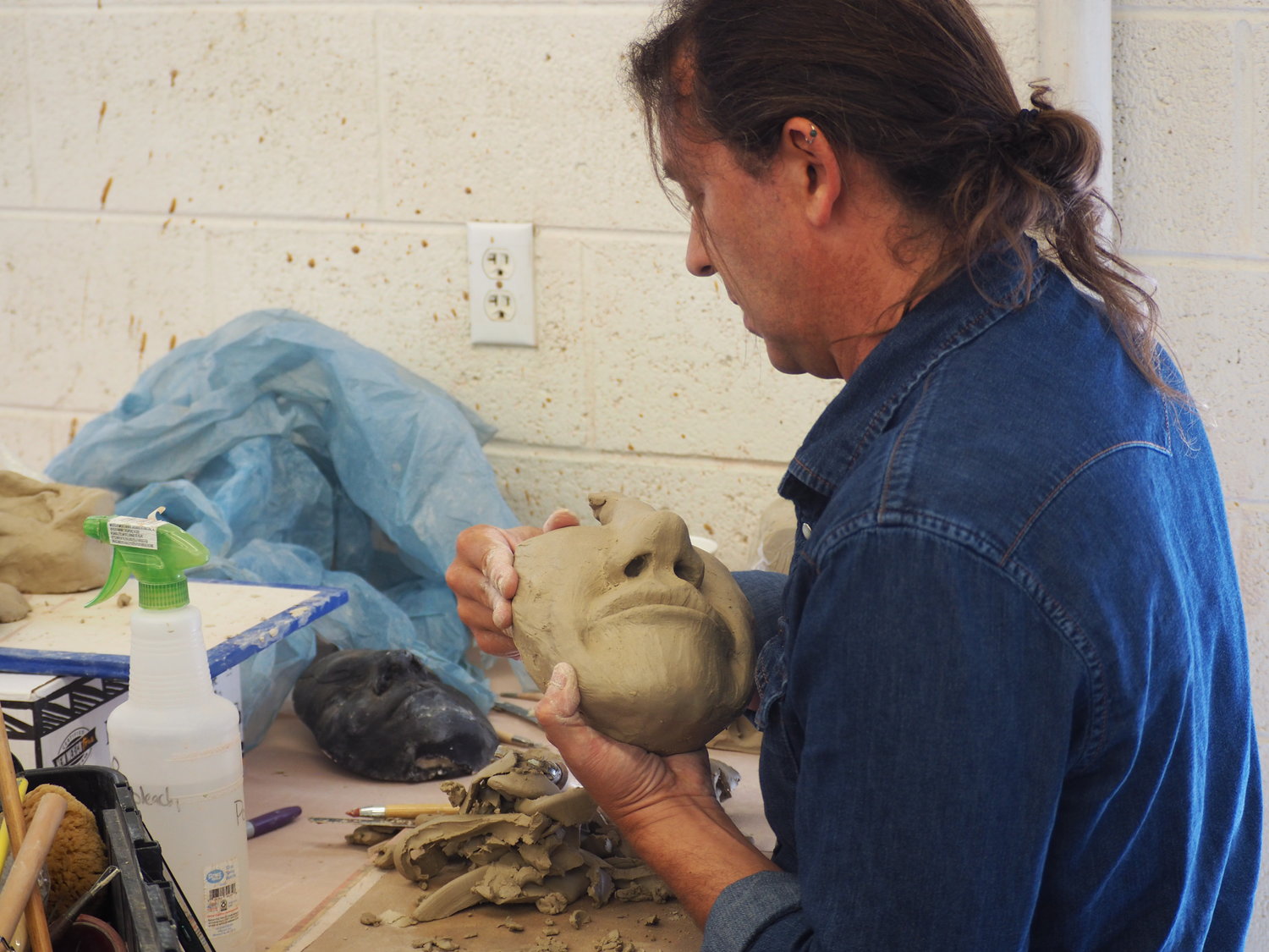 A workshop participant carefully details his self portrait clay mask at Western New Mexico University.