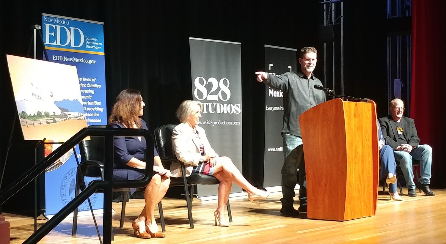 828 Productions CEO and founder Todd Lundbohm points to an artist’s rendering of the film studio he will bring to Las Cruces. With him on stage at the Rio Grande Theatre during the announcement were, left to right, Las Cruces Mayor Pro Tempore Kasandra Gandara, Gov. Michelle Lujan Grisham and state Sen. Jeff Steinborn. On the other side of the podium is New Mexico Economic Development Dept. Sec. Alicia J. Keyes.