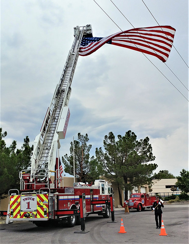 With the Las Cruces Fire Department’s giant garrison flag flying at Fire Station No. 1, a Las Cruces firefighter walks point Sunday morning, Sept. 11, in commemoration of the 911 attacks.