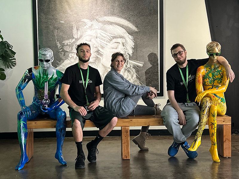 Rubin Bustamante, Malu Bender and Ron Bender hang out in the lobby at MasBuds with personifications of Sativa and Indica on either side of them. Sativa and Indica are the two main types of cannabis as they are used for medicinal and recreational purposes.