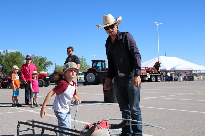 A New Mexico State University rodeo team member teaches a young AG Day attendee how to rope at a previous year’s event.