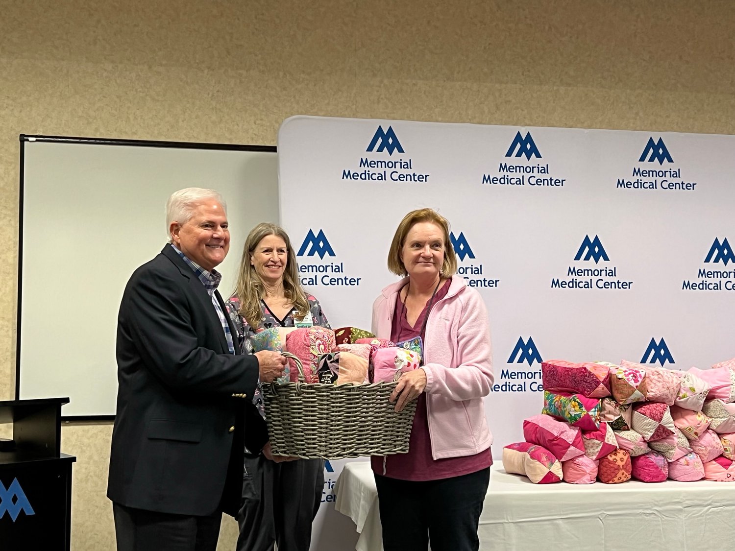 Memorial Medical Center CEO John Harris and Cancer Center Manager Lynn Fletcher accept a gift of 217 hand-made pillows for cancer patients from Las Colcheras Quilt Guild co-president and breast cancer survivor Dianne Herrmann during an Oct. 28 presentation.