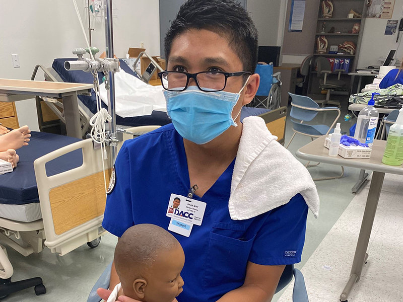Doña Ana Community College nursing student Ryan May holds an infant mannequin as part of training in a nursing course at DACC.