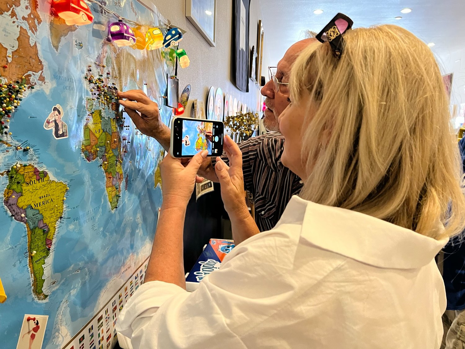 Ukrainian born Alla California, examines her hometown on a map on the wall at Downtown Blues Coffee. Her husband, Donald Jackson, places a pin on the town of Luhansk where she is from.