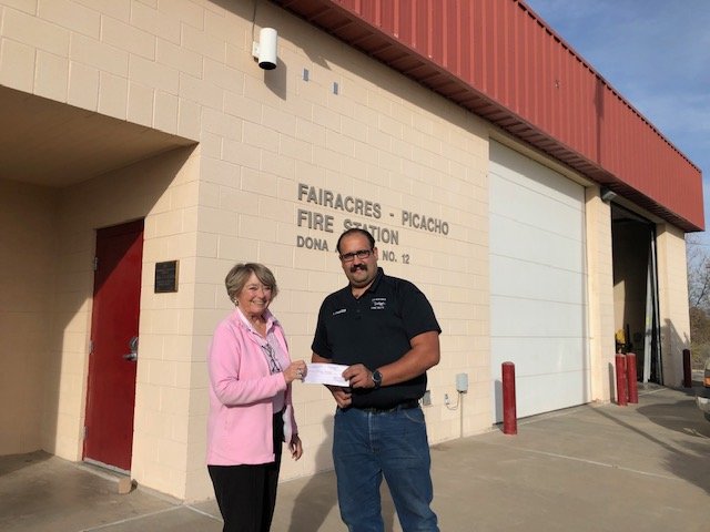 Picacho Hills Property Owners Association board member Pat Anderson presents a $200 donation from the association to Fairacres Volunteer Fire Department Assistant Fire chief Austin Standride.