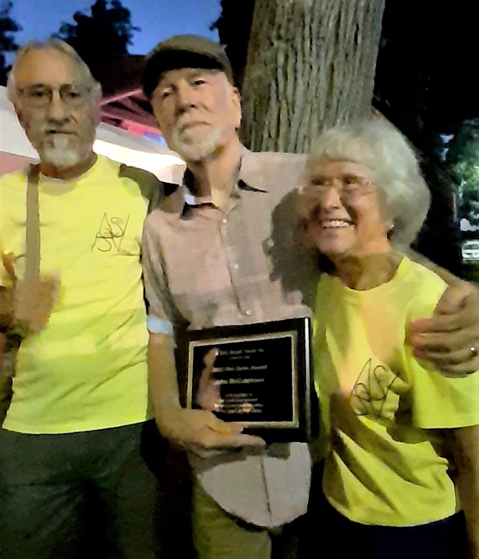 2022 Phil Ochs Award winner John McCutcheon, a six-time Grammy nominee, center, with Ron and Kathy Cooke