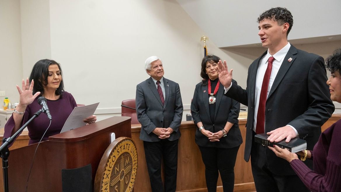 Doña Ana County Clerk Amanda Lopez Askin, left, swears in New Mexico State University Student Regent Garrett Moseley March 10 as Regent Chair Ammu Devasthali, right, holds a Bible for him. NMSU Chancellor Dan Arvizu, center left, and newly confirmed regent Deborah K. Romero look on.
