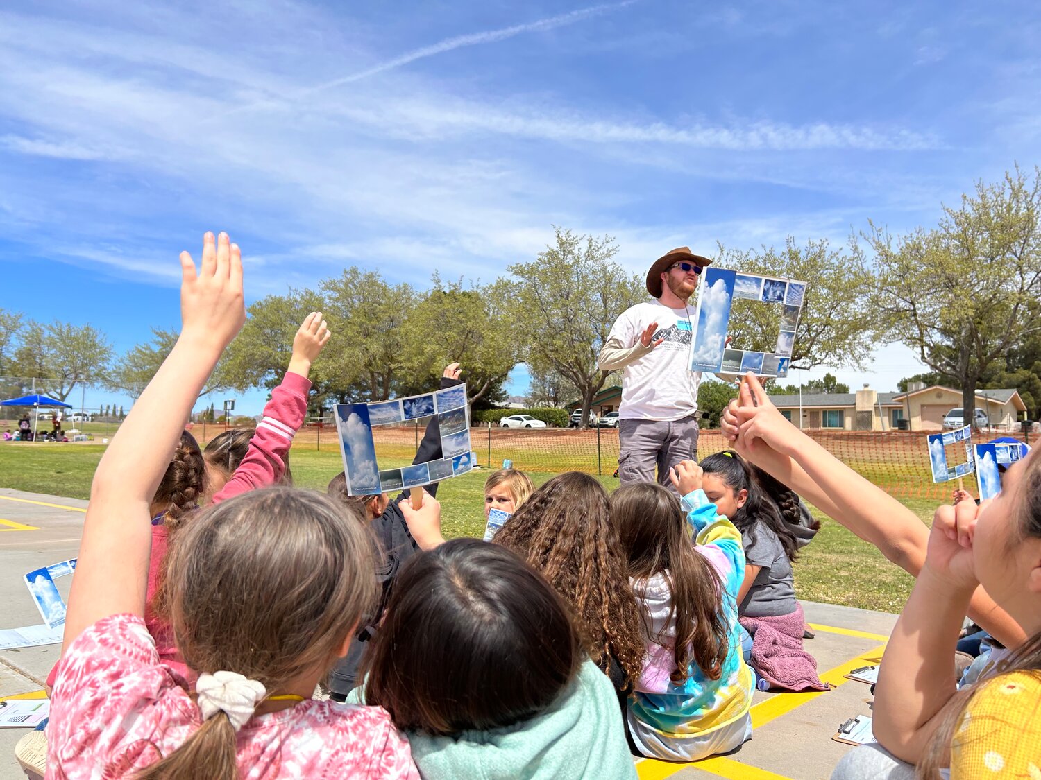 Asombro Program Leader Ryan Pemberton, guiding Doña Ana Elementary School third graders through a cloud identification activity to determine whether spadefoot toads could be living in the students' schoolyard.