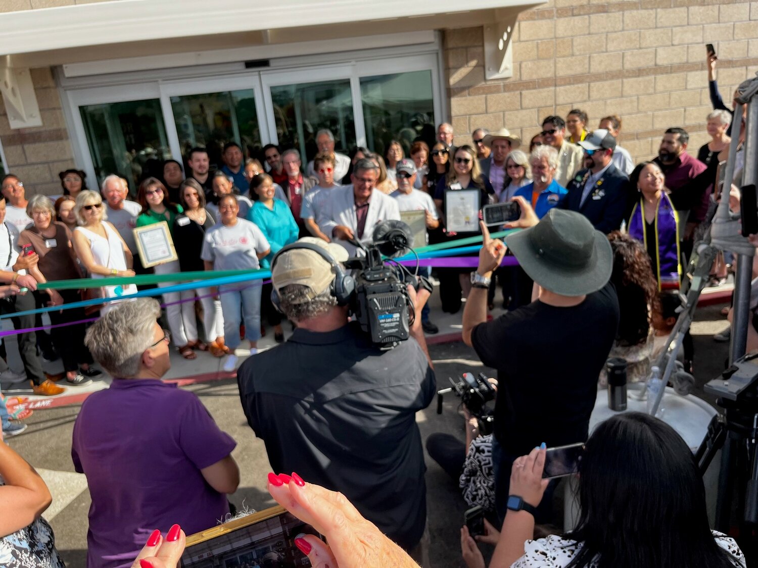 Lorenzo Alba Jr., executive director of Casa de Peregrinos, cuts the ribbon in front of dozens of cameras at the facility’s grand opening.