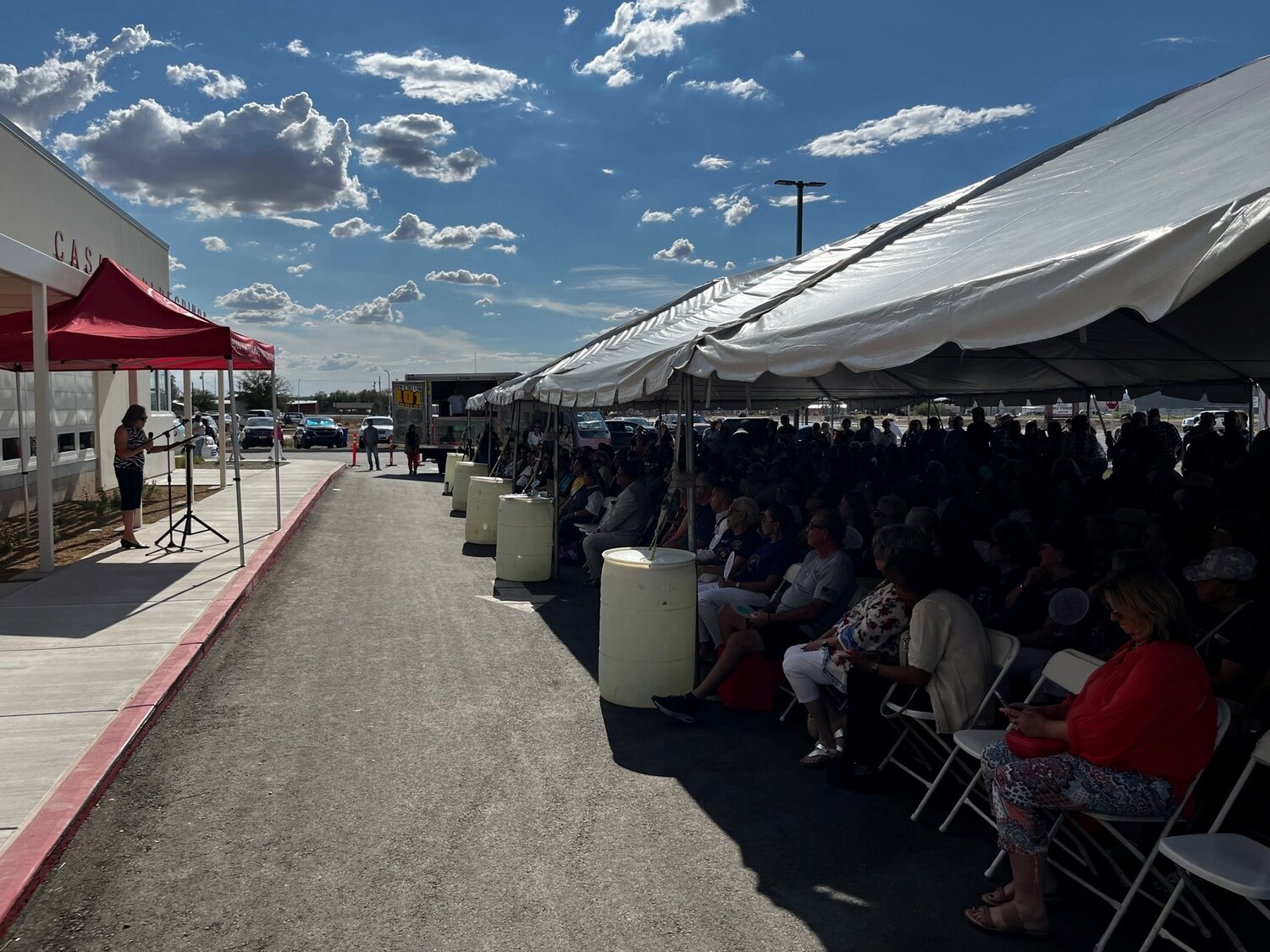 Hundreds of visitors gather under a tent in the parking lot to hear speakers look back as well as forward on the history and future of Casa de Peregrinos.