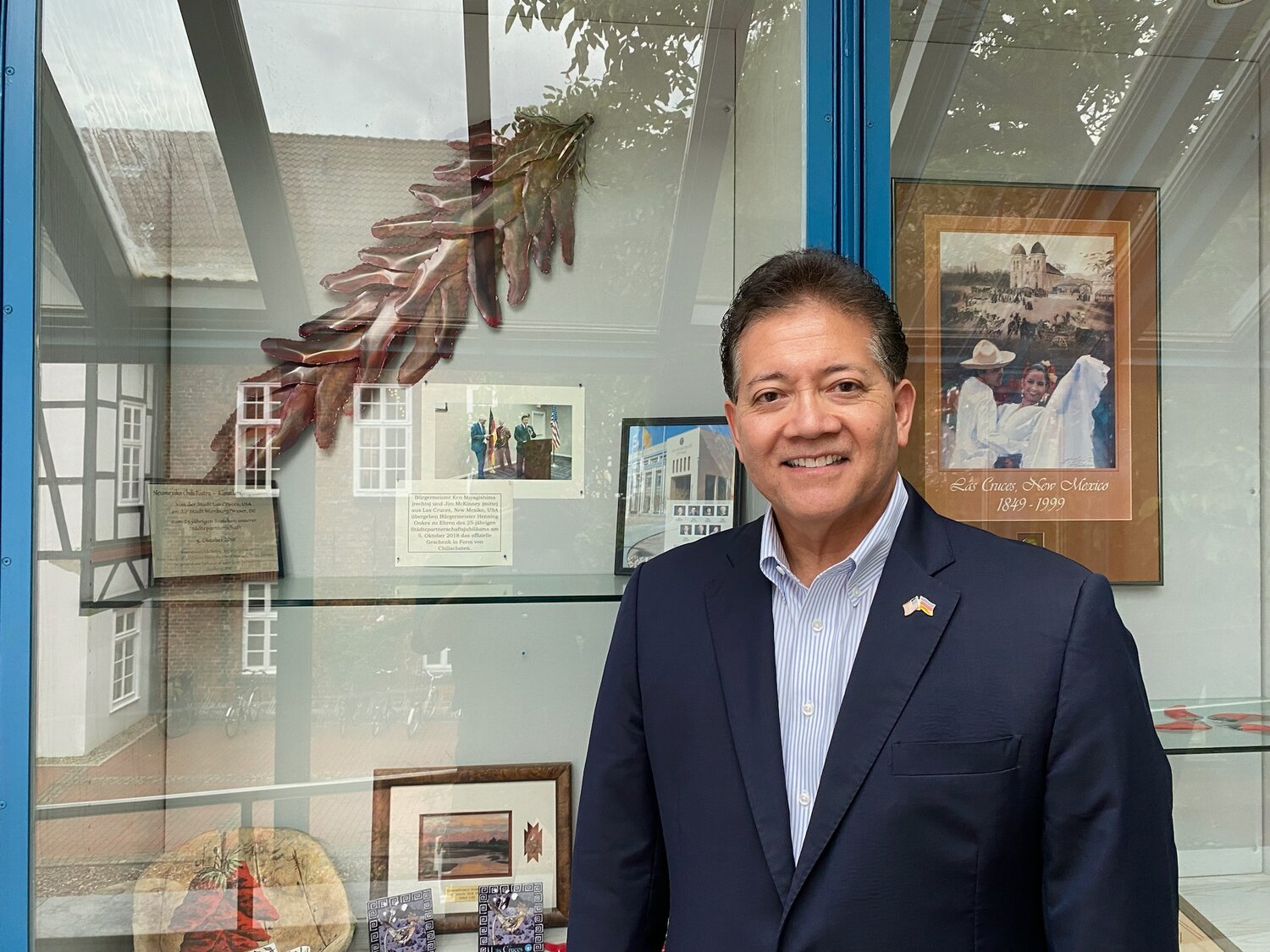 Las Cruces Mayor Ken Miyagishima, with photos of Las Cruces City Hall on the wall behind him.