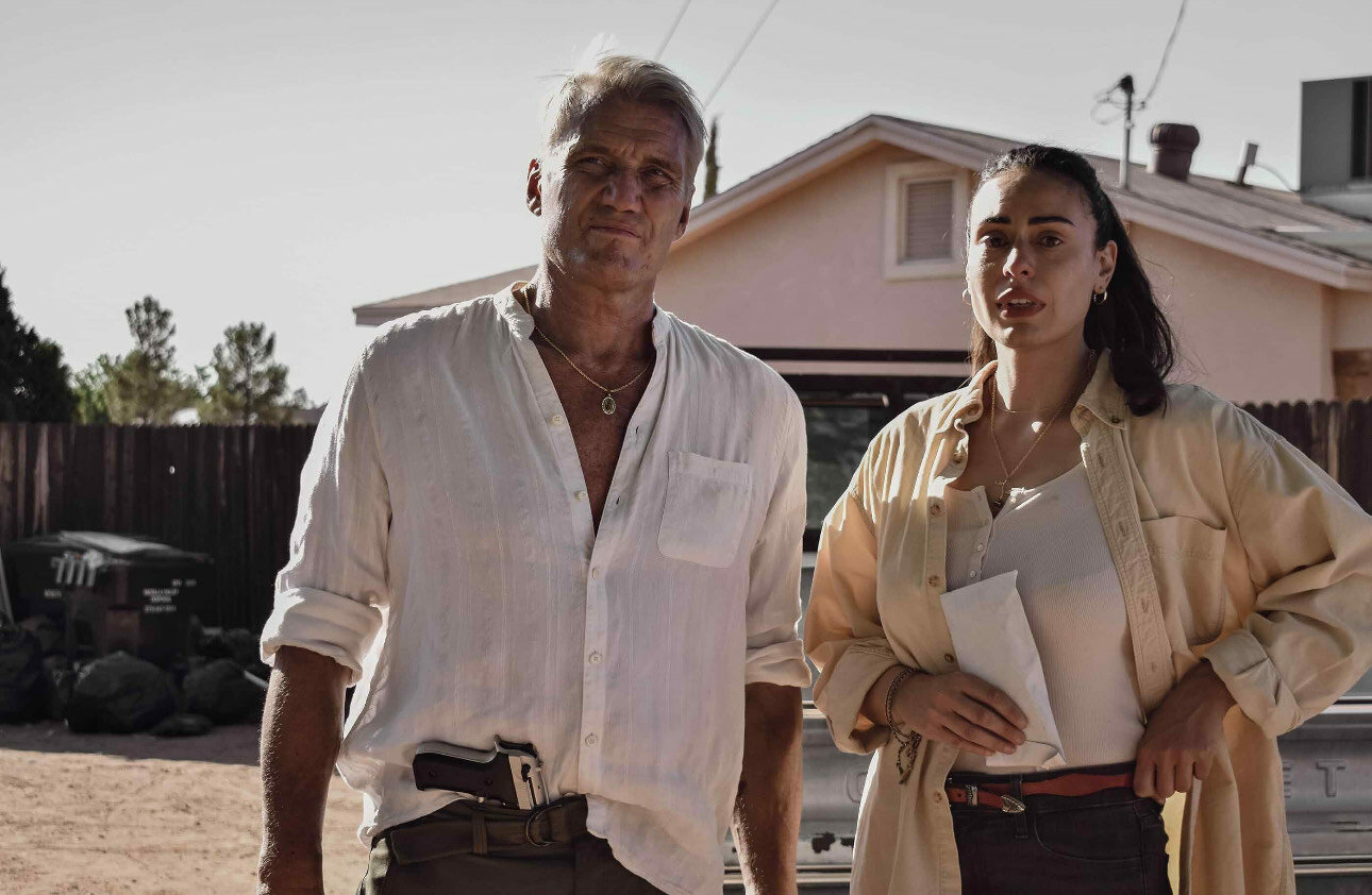 Christina Villa is serious on the set of “Wanted Man” with her director and costar Dolph Lundgren.