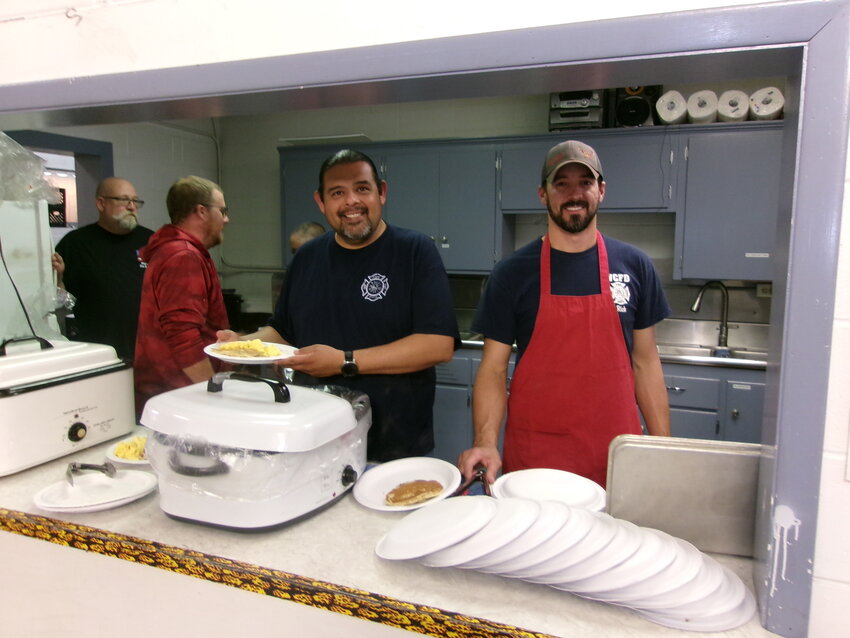 Firemen serving pancakes, scrambled eggs and sausages