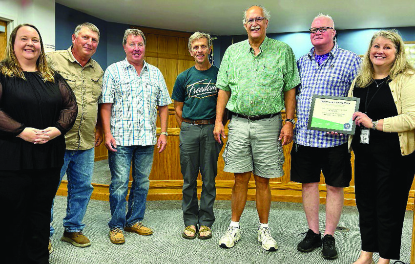 Housing Director Joy Watson, right, holds an award certificate from the National Association of counties, commending the county for its work on the Twin Oaks housing development. Also pictured, from left, are Administrator Sara Folsted, and Commissioners Charlie Peters, Jim Purfeerst, Gerry Hoisington, Steve Underdahl and Galen Malecha.