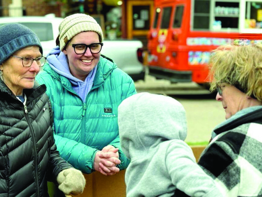 Holly Schoenbauer, center, speaks with a foster mother 
during a May event in Bridge Square in Northfield to raise 
awareness of her organization and foster care in general.