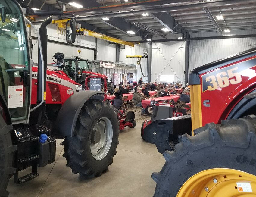 The Goodhue Day crowd sits between tractors and other equipment on display in Lodermeier's shop area.
