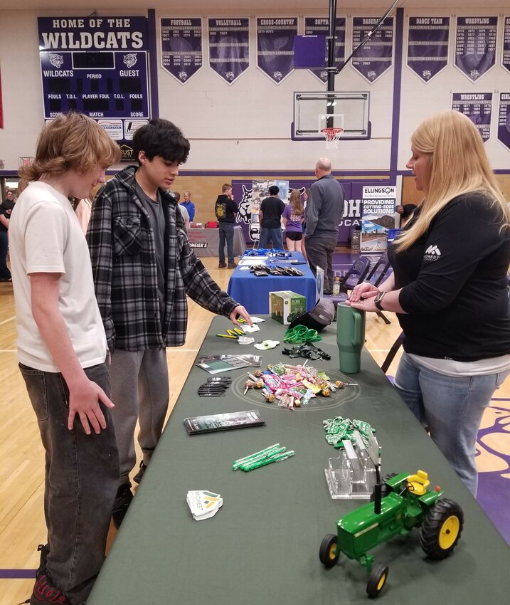 Marcy Sheridan informs two 8th grade students about the Midwest Machinery Company's tuition reimbursement program.