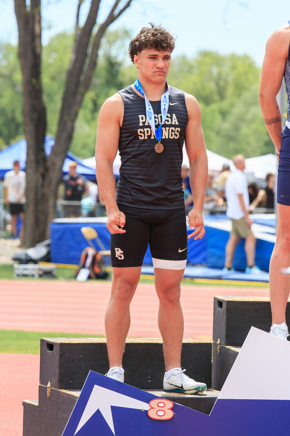 Colton Lucero stands on the podium after finishing eighth in the boys’ 100-meter dash.